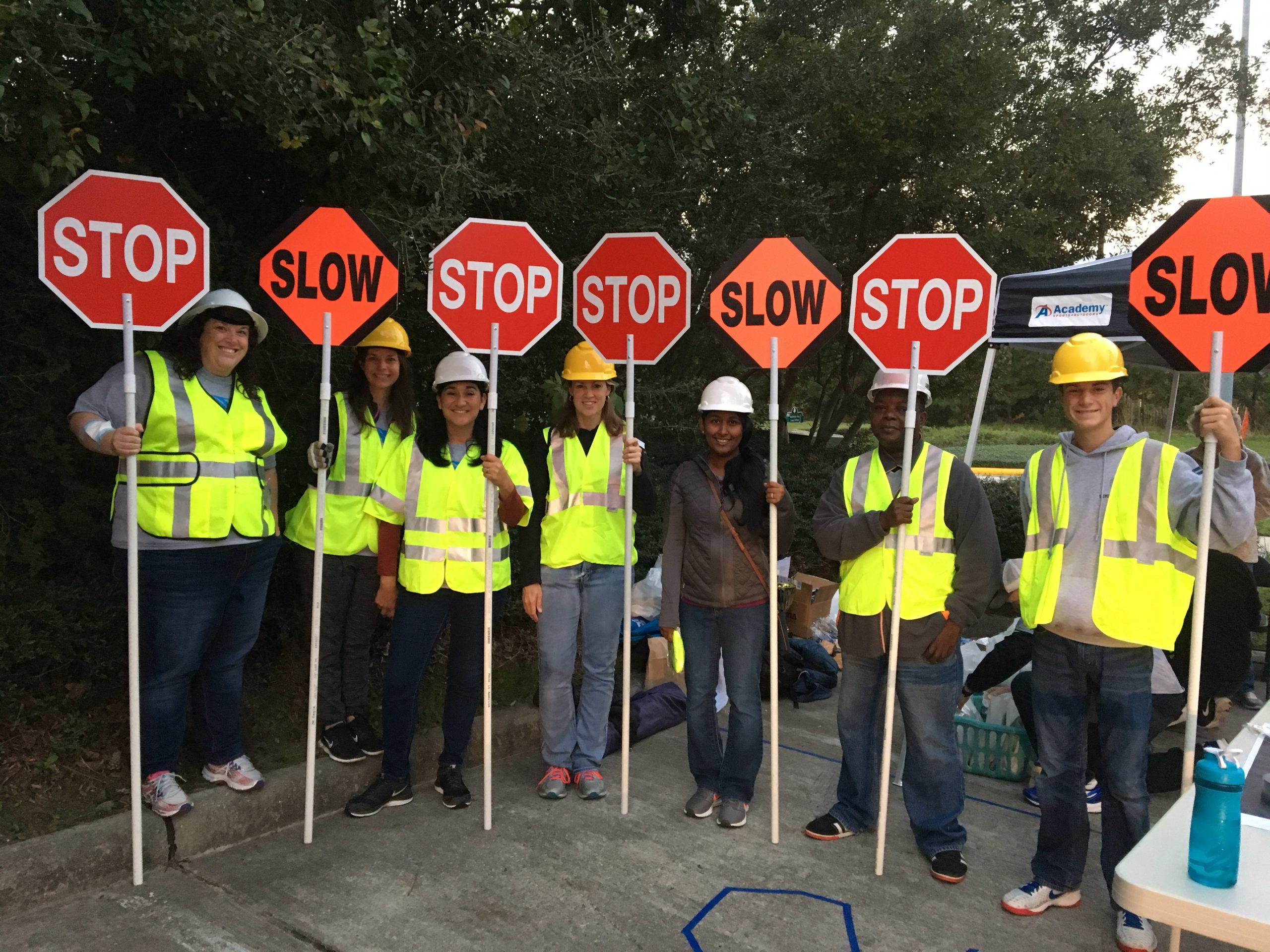 seven people standing in a line wearing construction gear holding stop signs